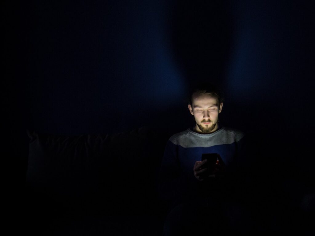 a male looking at his phone in the dark